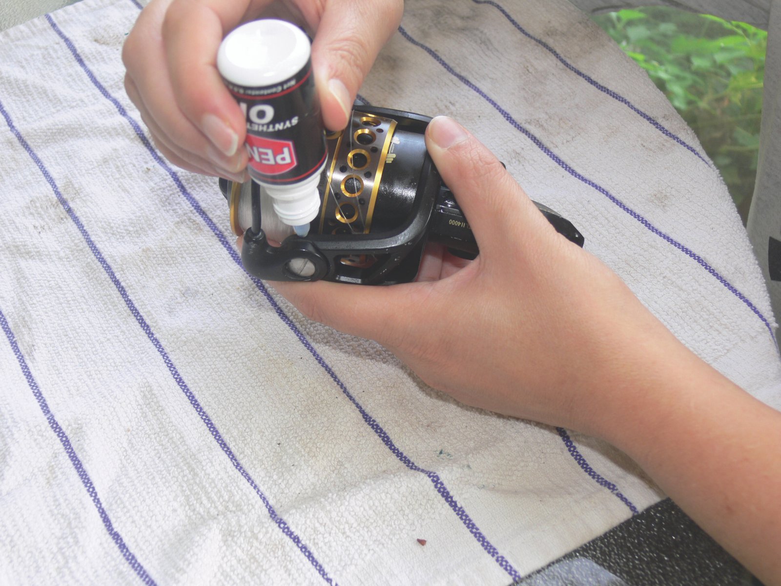 A comparison image showing oil being applied to a reel bearing and grease being applied to a main gear.