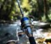 A balanced ultralight spinning reel and carbon fiber rod setup by a stream.